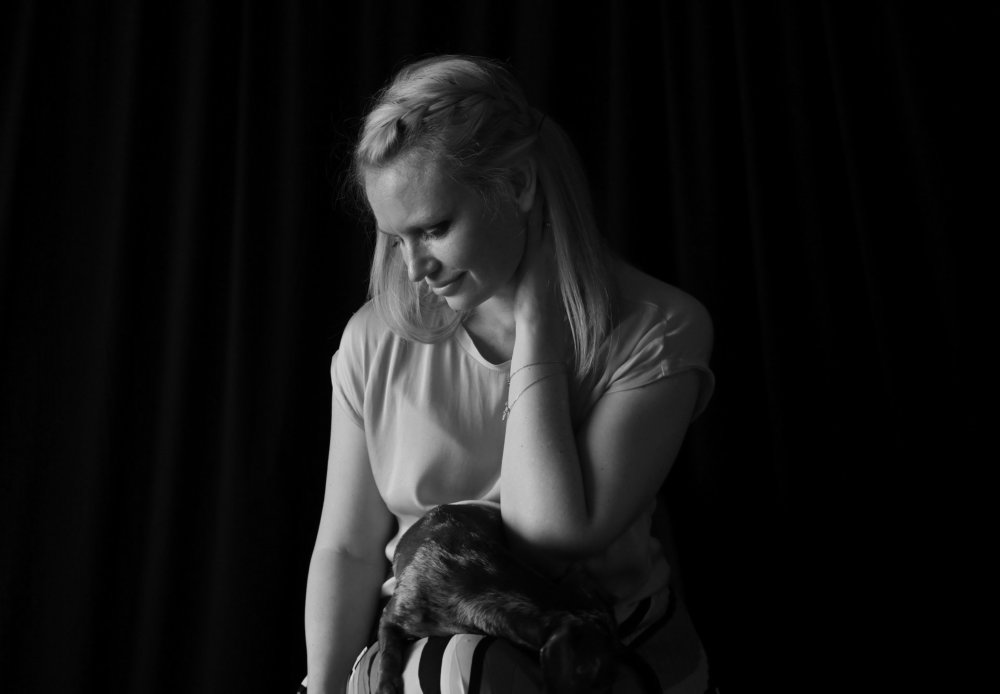 Black and white portrait of a young lady, looking down, with her dog on her lap