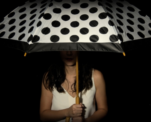 Portrait of girl holding an umbrella, with only the mouth being revealed as the rest of her is in shadow